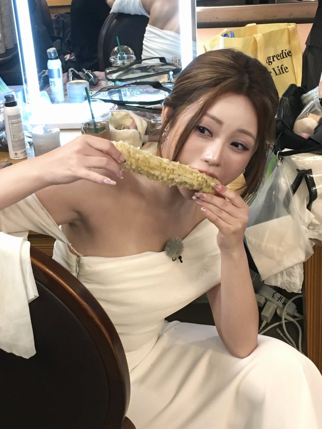 Hong Ji-yoon, wearing an off-shoulder dress, holds corn and snaps a photo... 