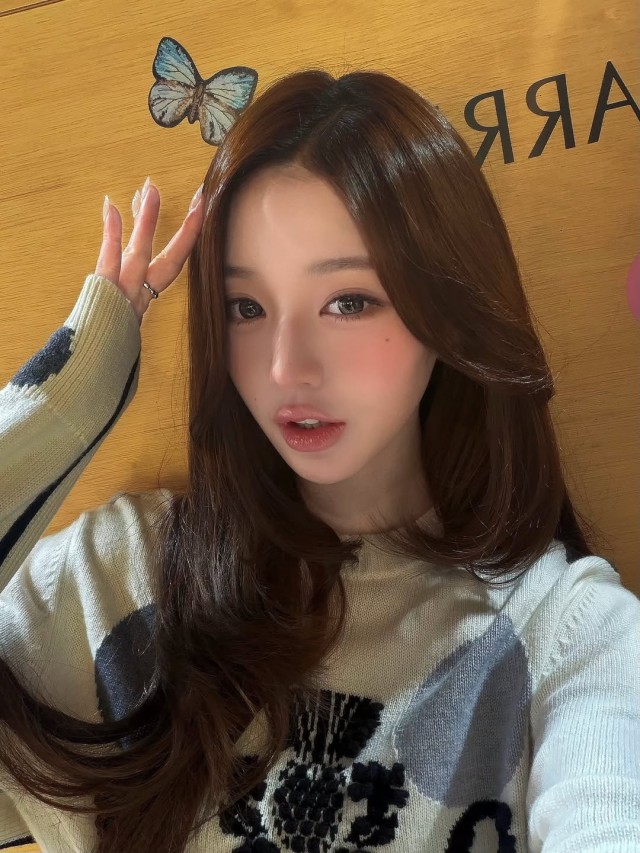Wearing a white sweater and showing off a butterfly motif... Jang Wonyoung exudes a lovely charm